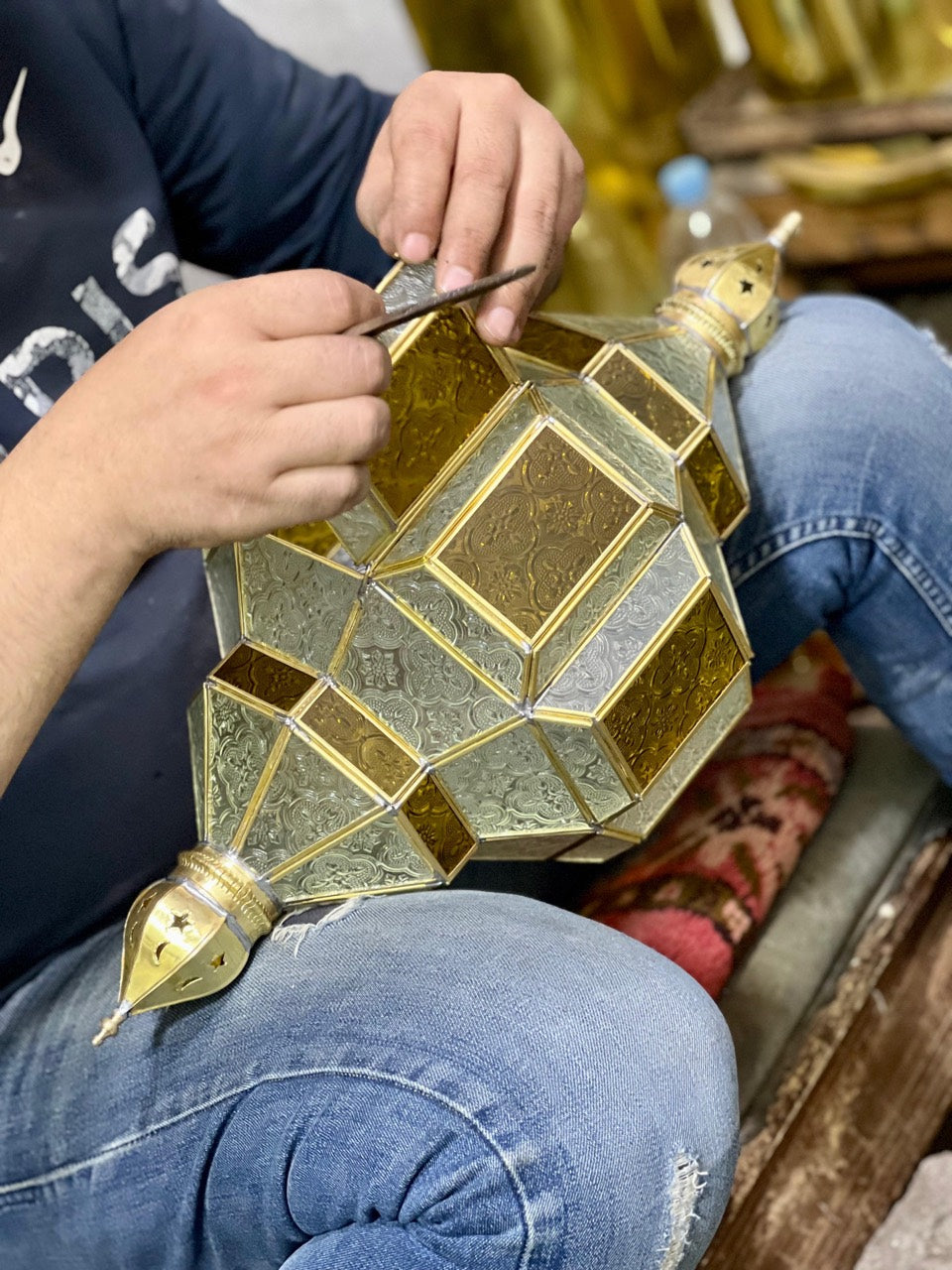 Artisan working on the edge of a decorative metal and glass lantern