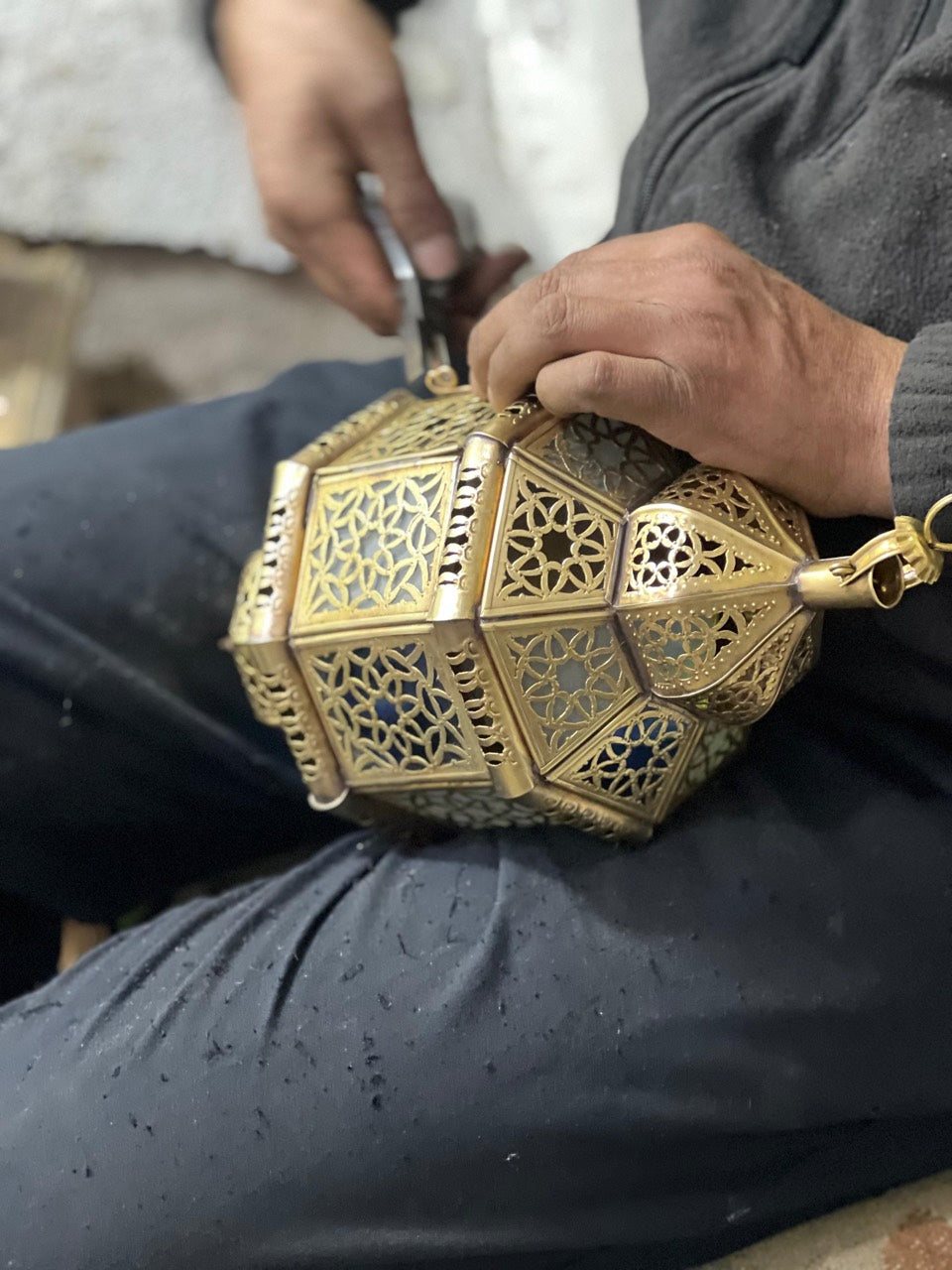 Artisan assembling the detailed metal panels of a Maison Azzar lantern by hand