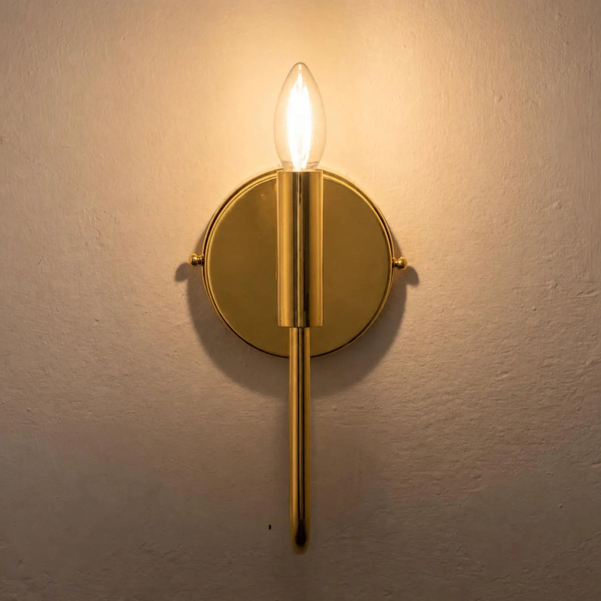Illuminated brass wall sconce shown without a shade