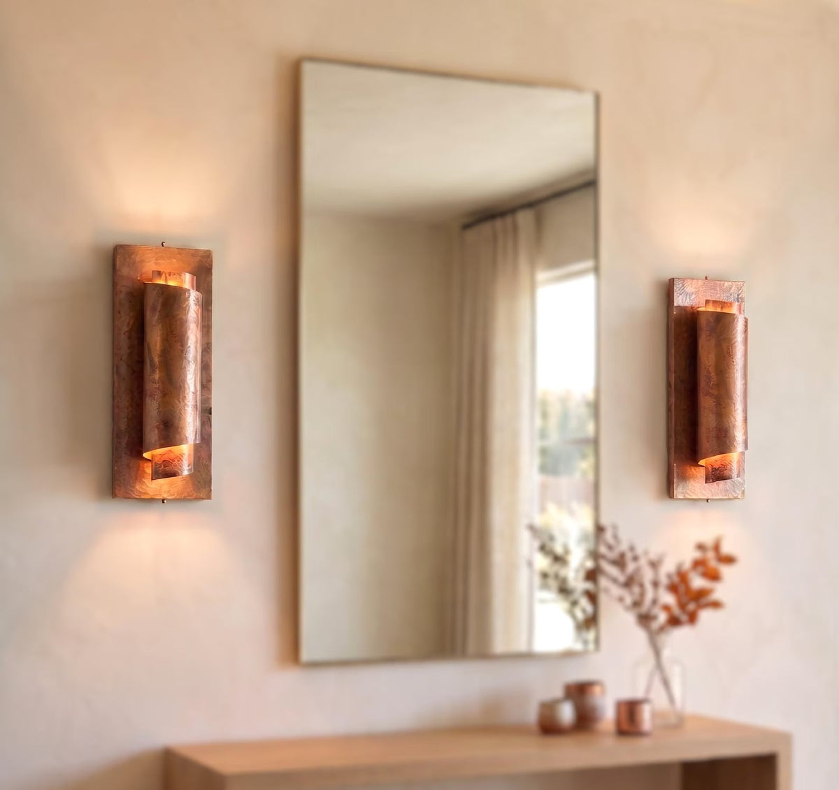 Two antique copper wall sconces displayed beside a mirror