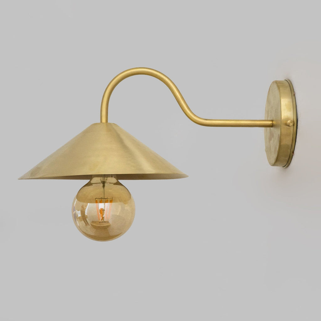 Side profile showing the curved brass wall arm and conical shade