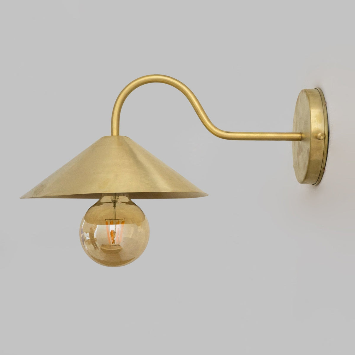 Side profile showing the curved brass wall arm and conical shade