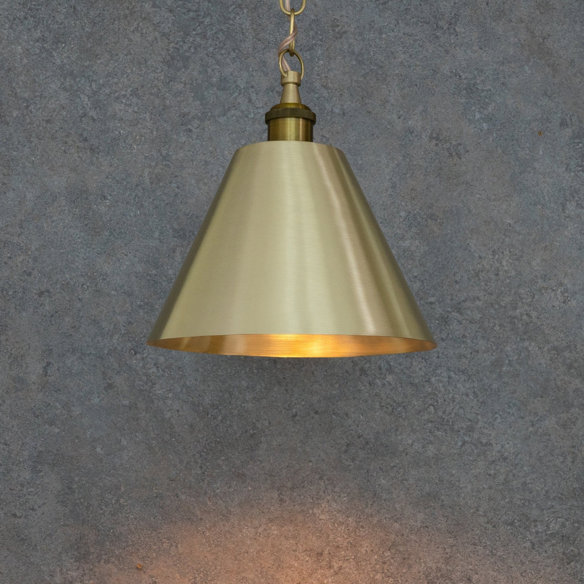 Illuminated brass cone pendant casting light downward