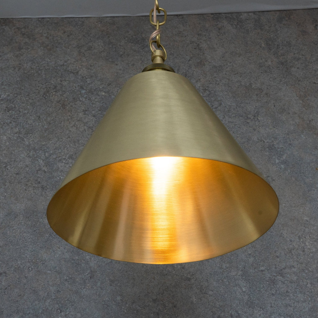 Brushed brass cone pendant showing the warm brass interior and chain suspension