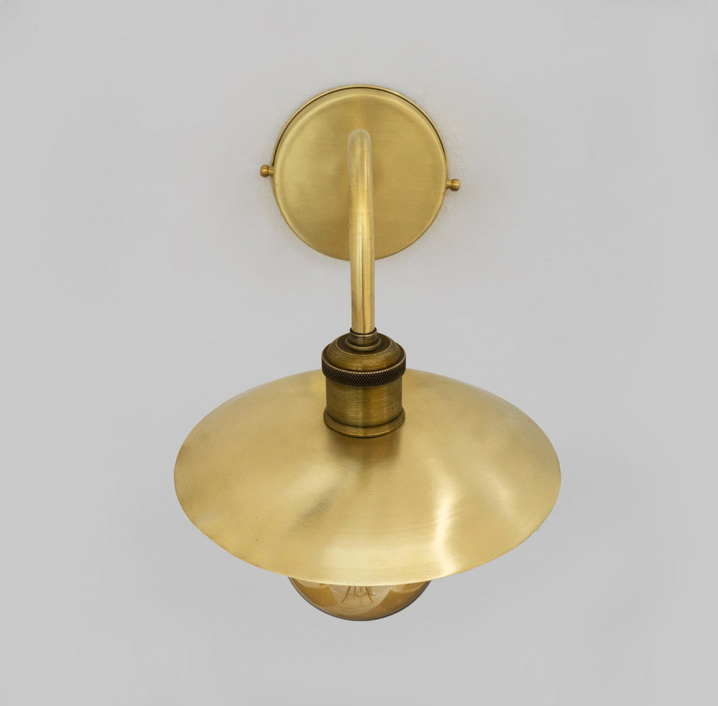 Upper view of the shallow brass shade and curved wall arm