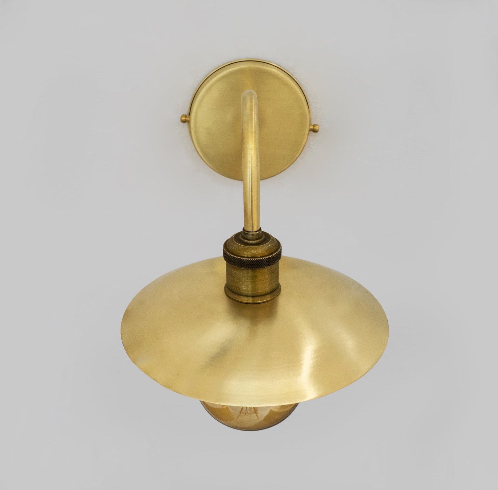 Upper view of the shallow brass shade and curved wall arm