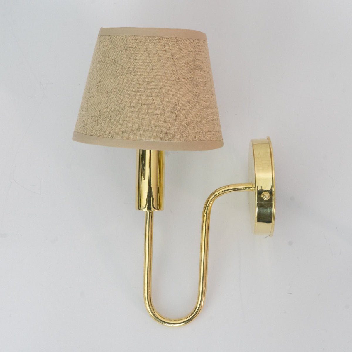Brass wall sconce with a tapered fabric shade and curved lower arm