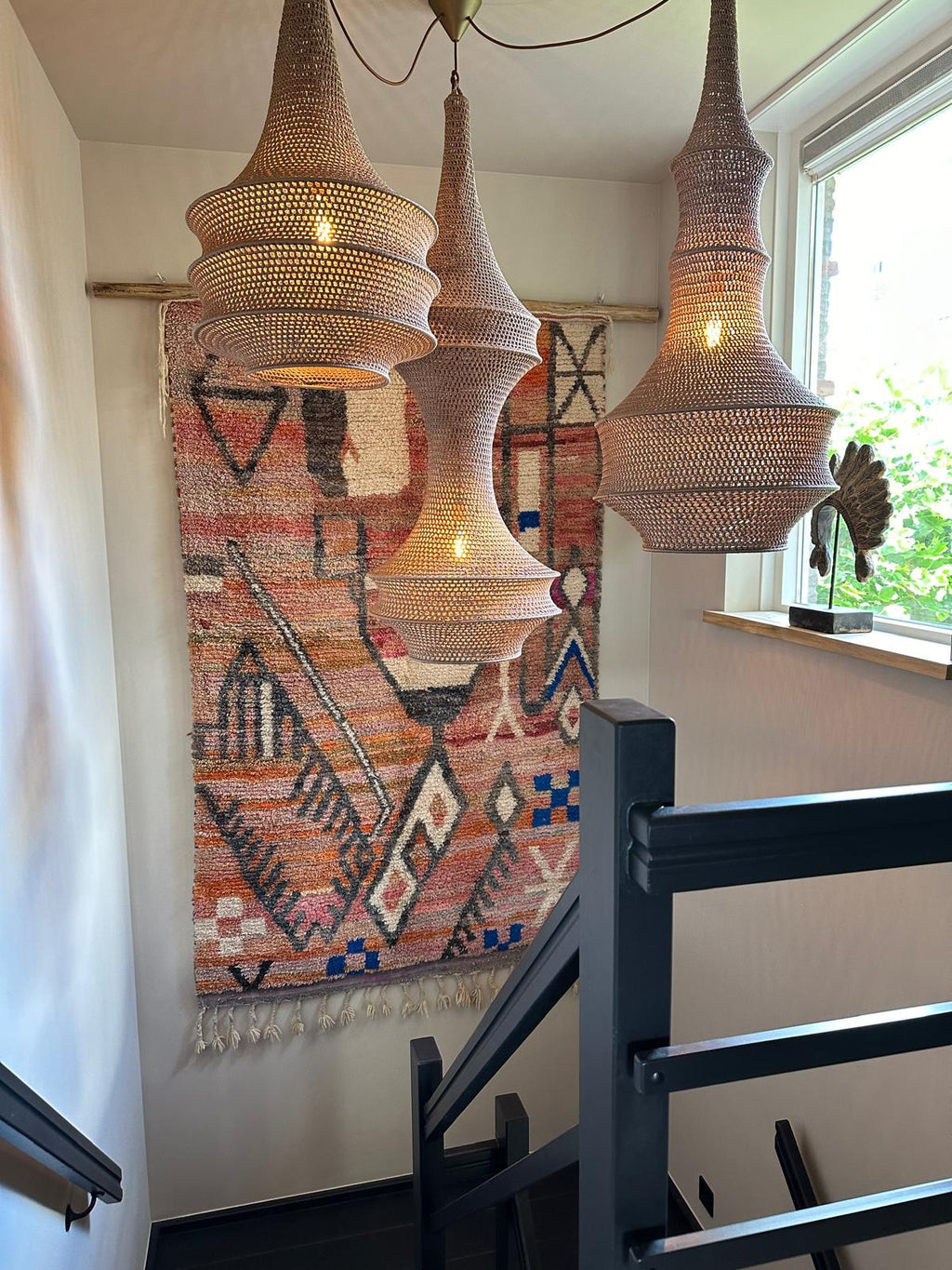 Three woven pendant lights with a light brown, textured finish and a tapered, multi-tiered silhouette. Each light fixture…