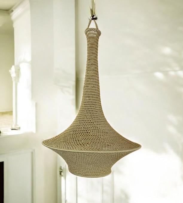 A beige, bell-shaped pendant light fixture featuring a detailed, intricate crochet pattern. The lamp has a narrow,…