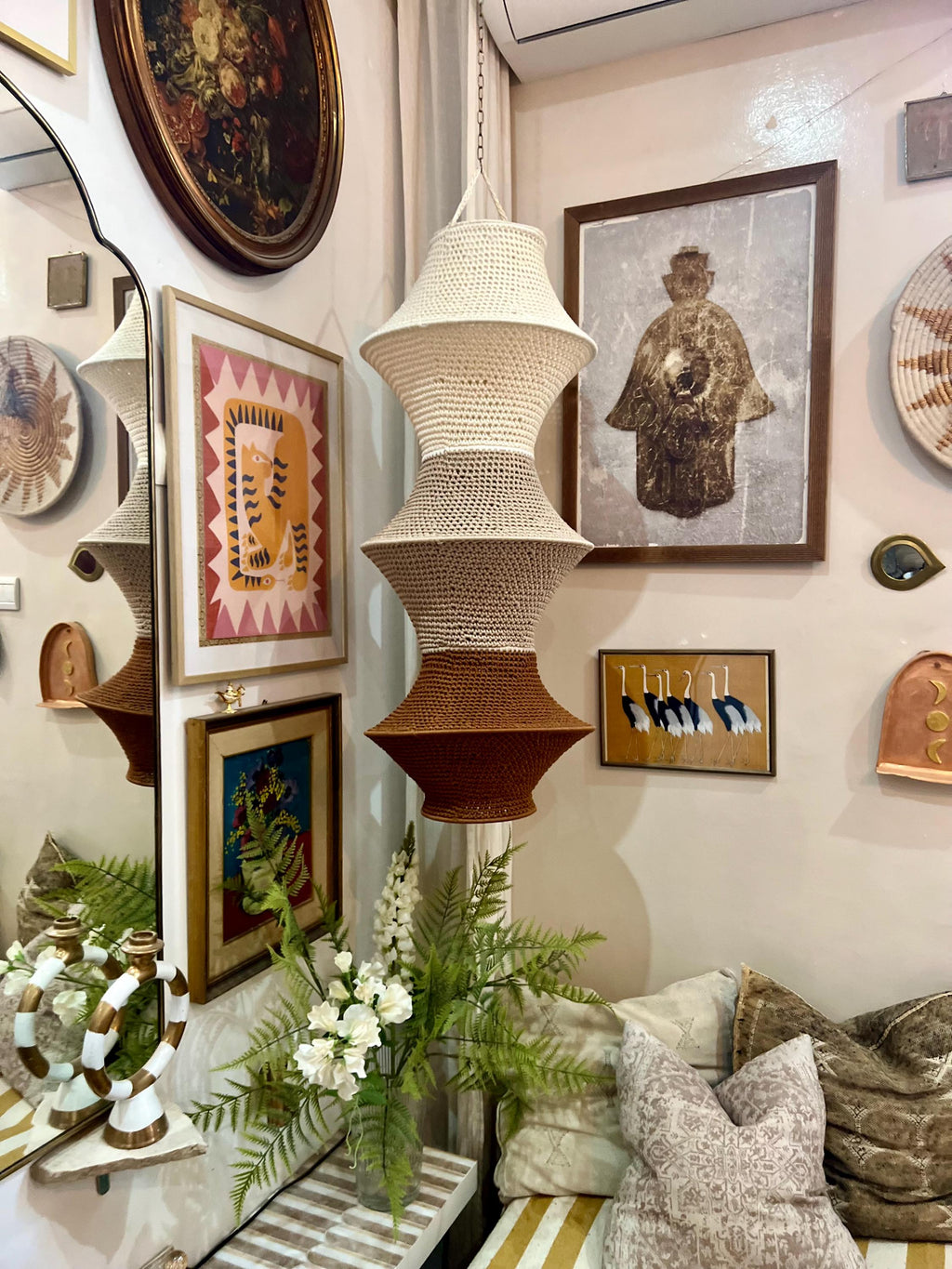 A three-tiered hanging pendant lamp shade featuring a crocheted texture. The design transitions in color from a cream…