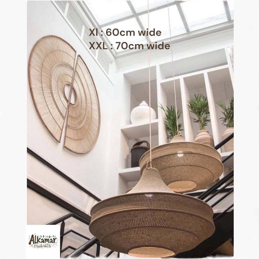 Two large, round, woven tan pendant lights with tiered, wide-brimmed shades hang from the ceiling. On the wall, a large,…