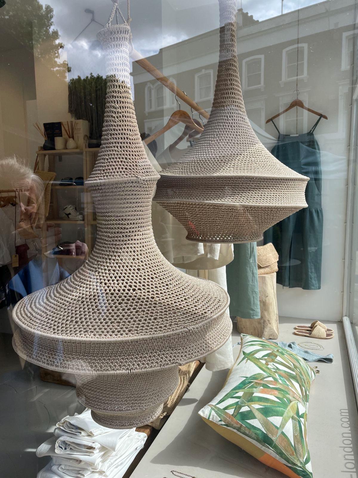 Two beige crochet pendant light shades with a wide, tiered, bell-shaped design. The shades feature a fine, open-weave…