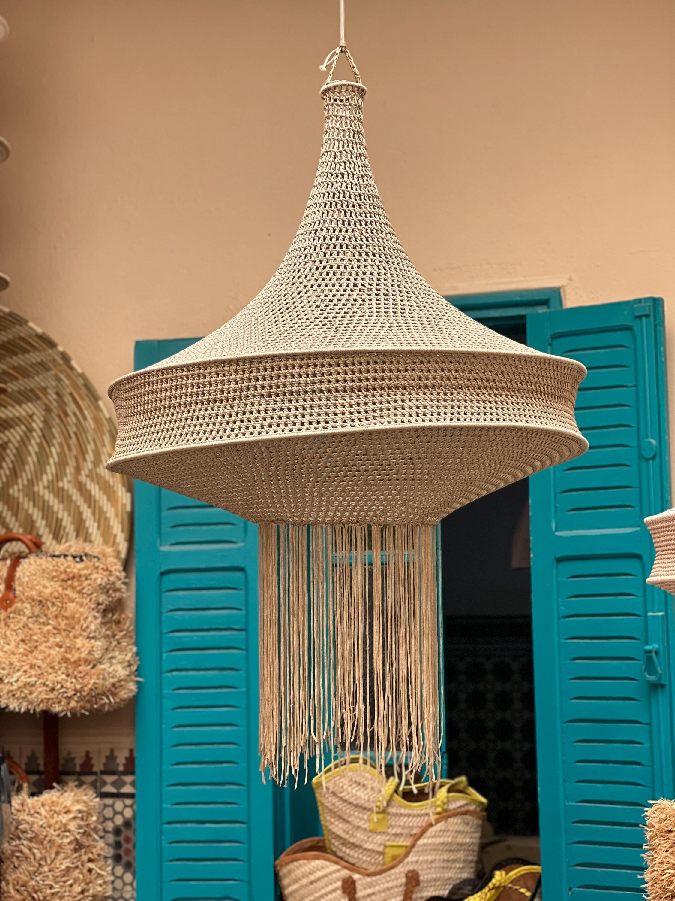 A beige, bell-shaped pendant light fixture crafted from tightly woven cord. The structure features a wide, tiered…