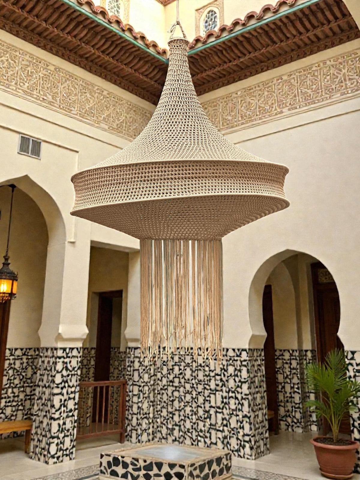 A large, beige, bell-shaped pendant light fixture crafted from woven cord. The structure features a wide, tiered circular…