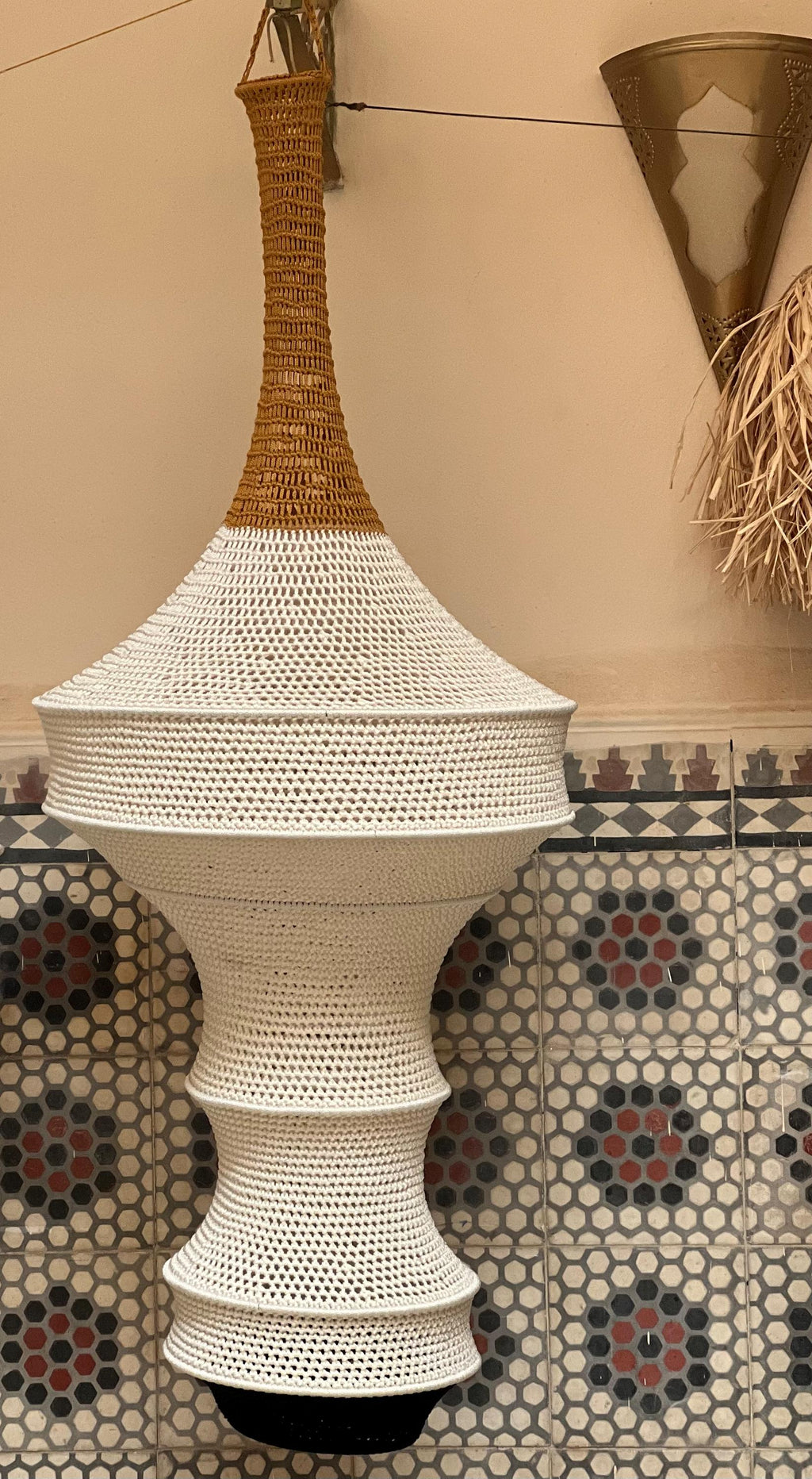 A hanging pendant light fixture featuring a tall, narrow neck in a warm mustard yellow hue, transitioning into a wide,…