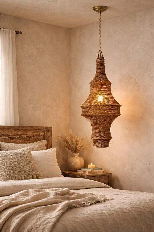 A brown woven pendant light fixture with a tapered, multi-tiered silhouette suspended from a brass-colored chain. The…