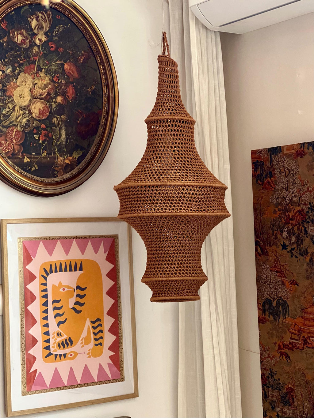 A hanging pendant light shade crafted from brown yarn in a crochet stitch pattern. The shade features a multi-tiered,…