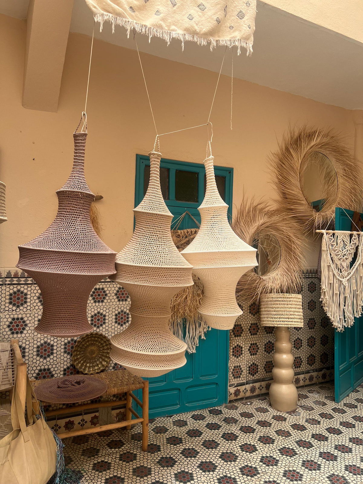 Three hanging pendant lamps with intricate crochet-style woven shades in varying shades of beige, tan, and light brown.…