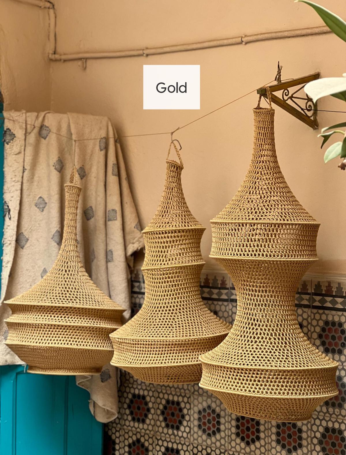 Three hanging pendant lamps made of woven tan material with a tiered, hourglass-like structure. Each lamp features a…