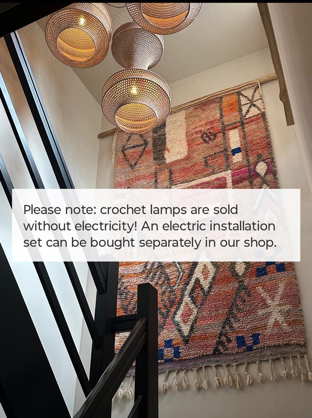 Three woven pendant lamps with a light brown finish hanging above a large, rectangular wall tapestry featuring a…