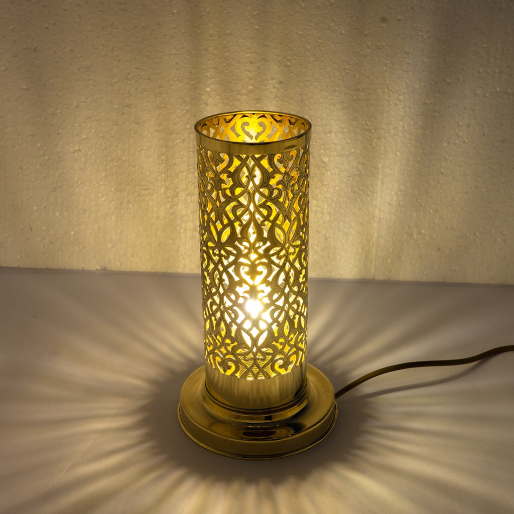 Illuminated brass table lamp casting patterned shadows on the wall
