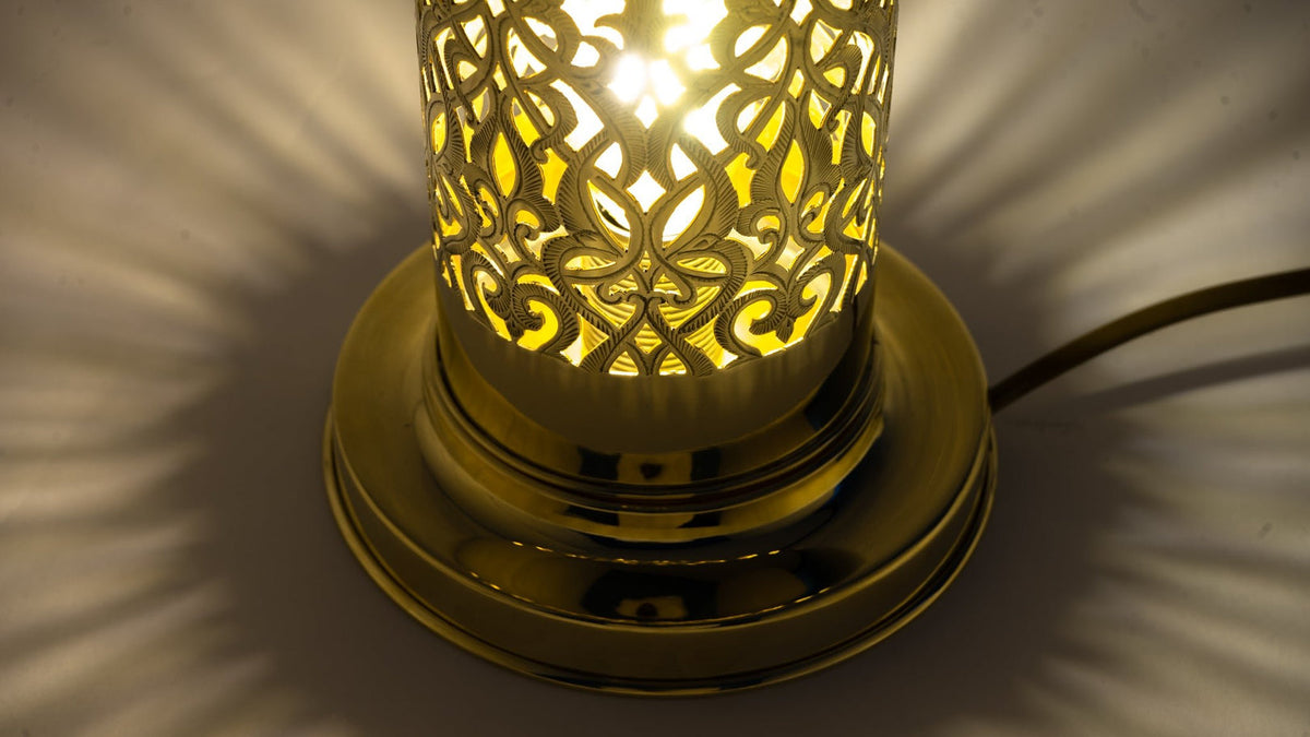 Lower angle of the lit brass lamp and its circular base
